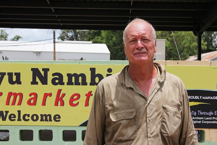 Recovery co-ordinator John de Koning standing in front of a community sign.