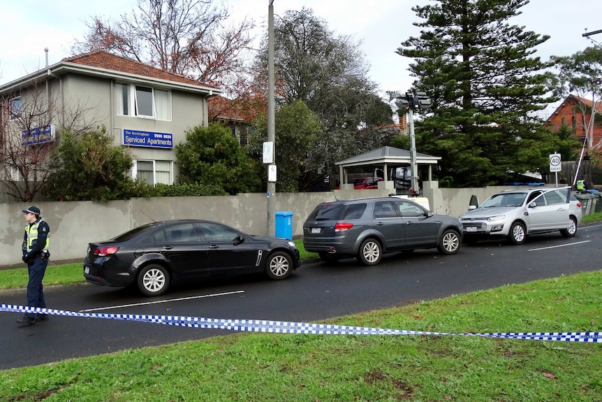 Police tape and a police officer at the Brighton siege scene the day after.