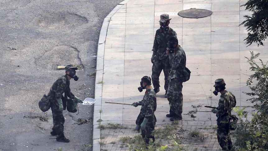 Chinese paramilitary police in gas mask examine chemicals at Tianjin blast site