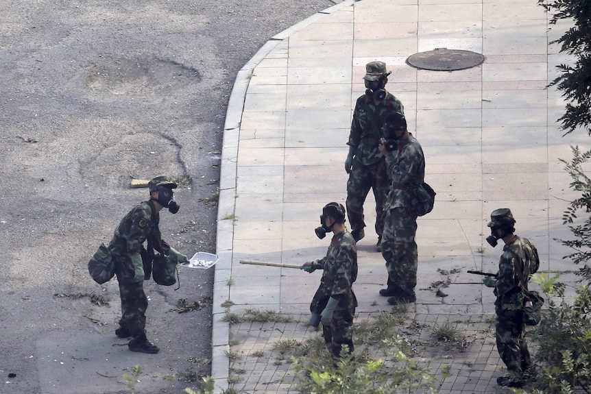 Chinese paramilitary police in gas mask examine chemicals at Tianjin blast site