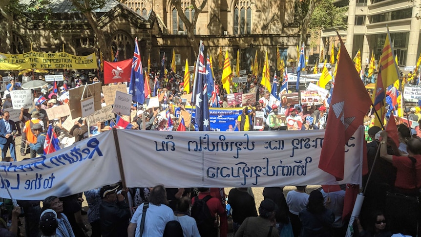 A crowd of people carry flags