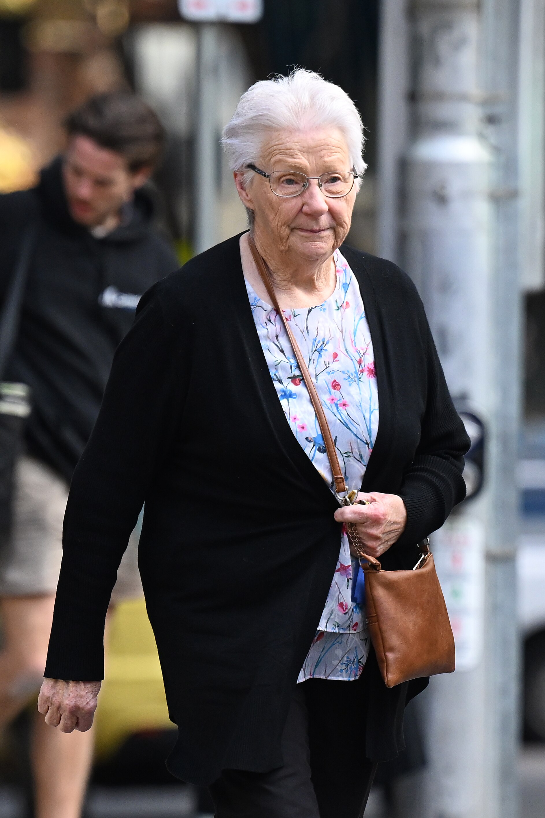 A woman looking sad while holding a bag in front of a court.