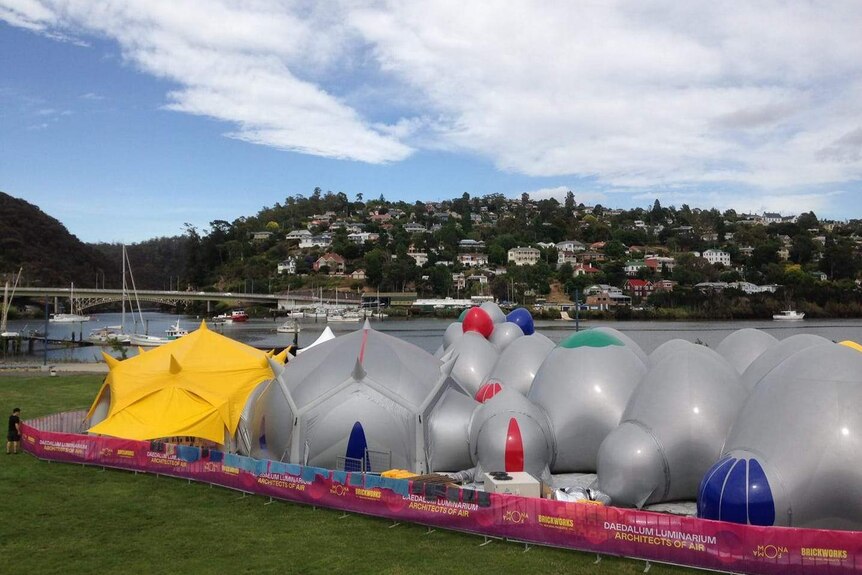 A grey inflatable maze with bulbous rooms set up alongside a river in Launceston