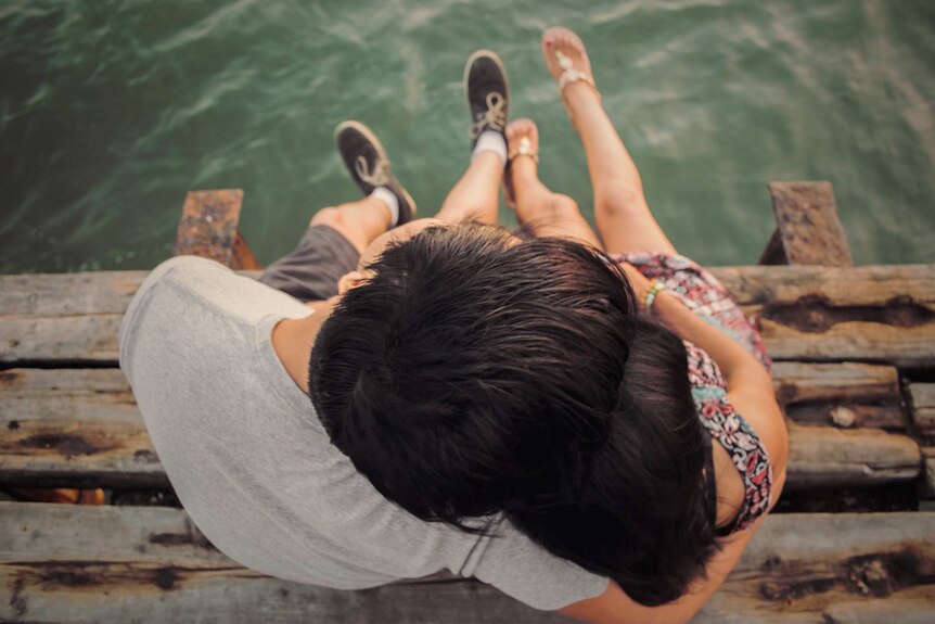 Couple sitting on a pier cuddling