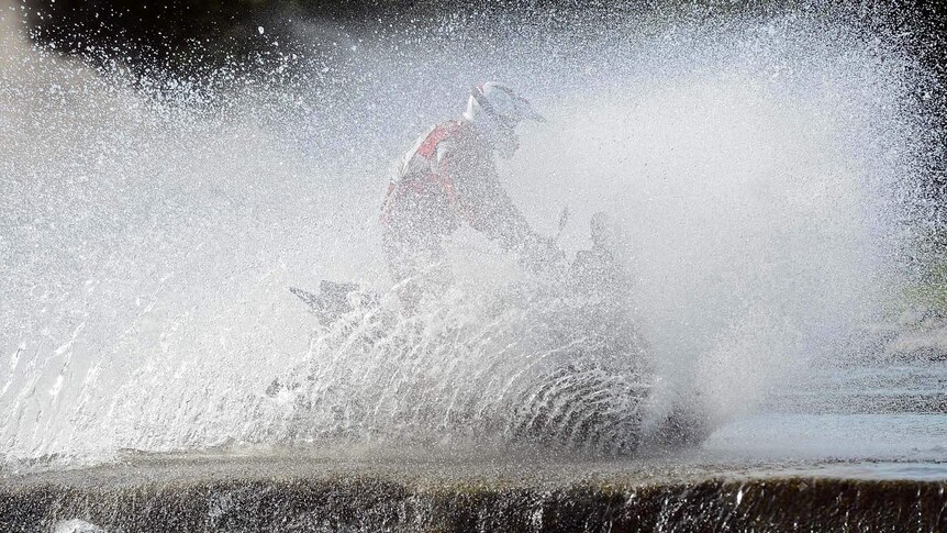 A quad-bike rider crosses water