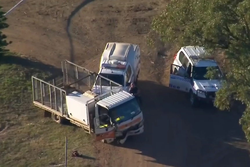 An aerial shot shows two police cars next to a truck that has crash damage.