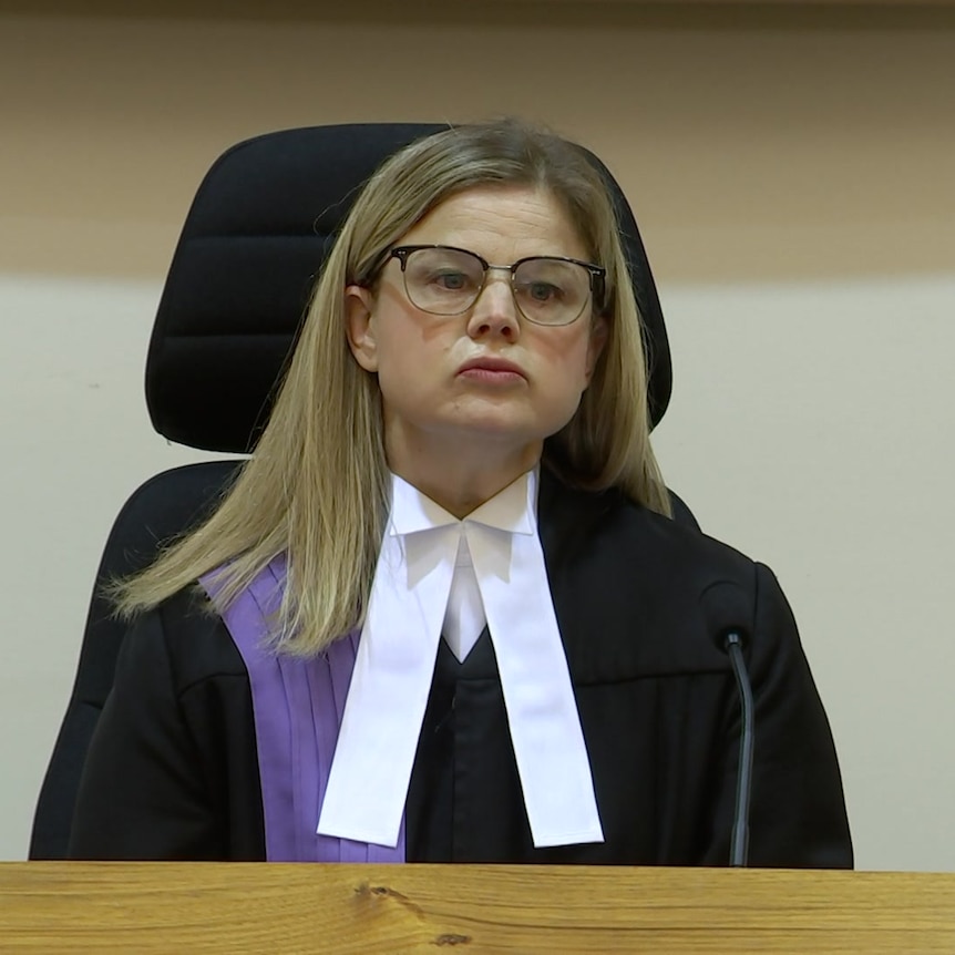 Een vrouw gekleed in een rechtersgewaad zit op de rechterbank