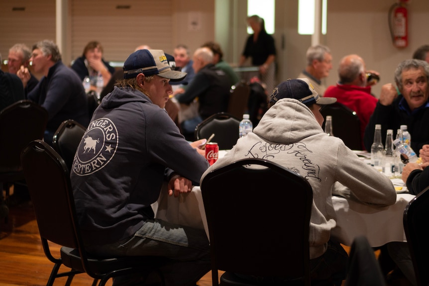 two young men sit a a table, talking.