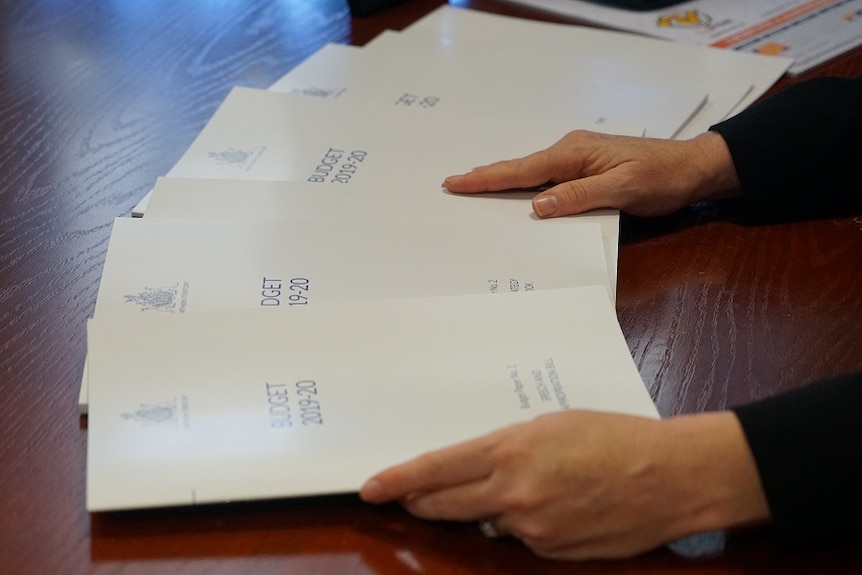 Hands rifling through budget papers.