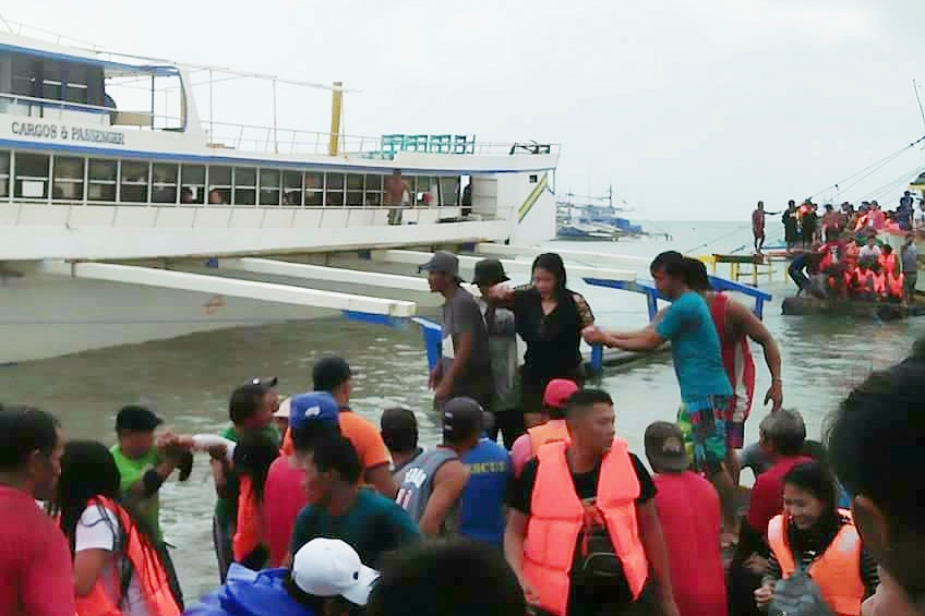Rescued passengers from the sunk ferry disembark from a rescue boat.