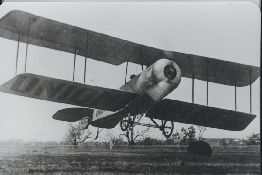 Black and white photo of the Kalgoorlie Biplane taking off.