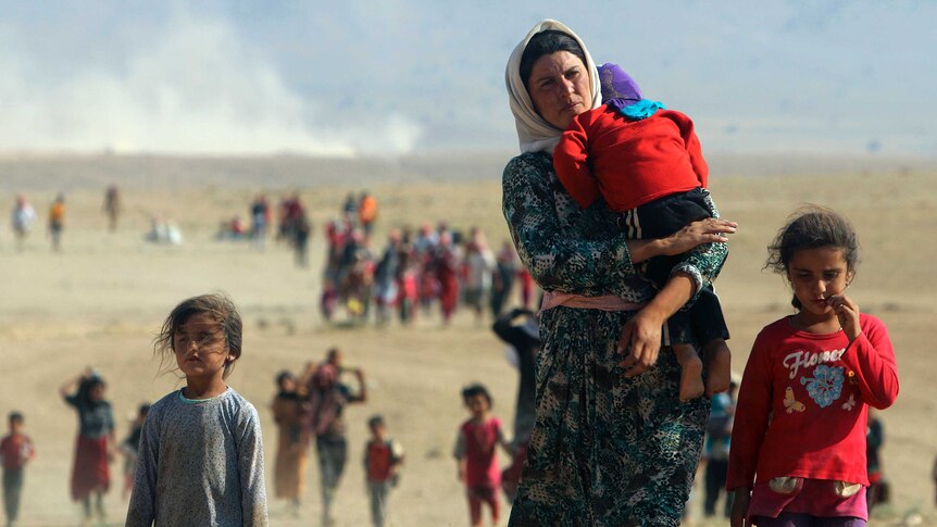 Displaced Yazidis walk towards the Syrian border