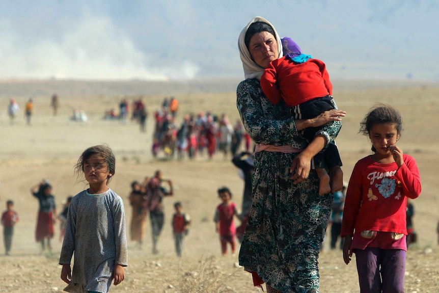 Displaced Yazidis walk towards the Syrian border