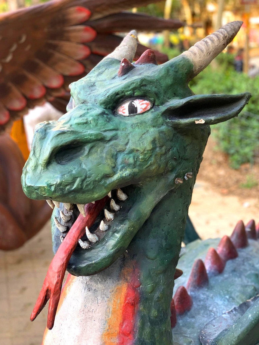 A horned dragon is painted green with a red tongue.