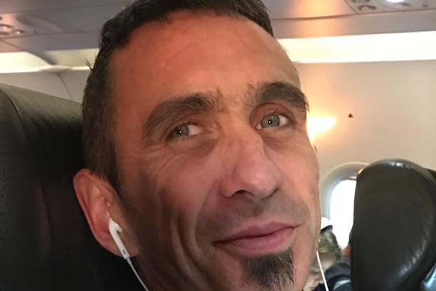 Man in a plane seat with earbuds in.