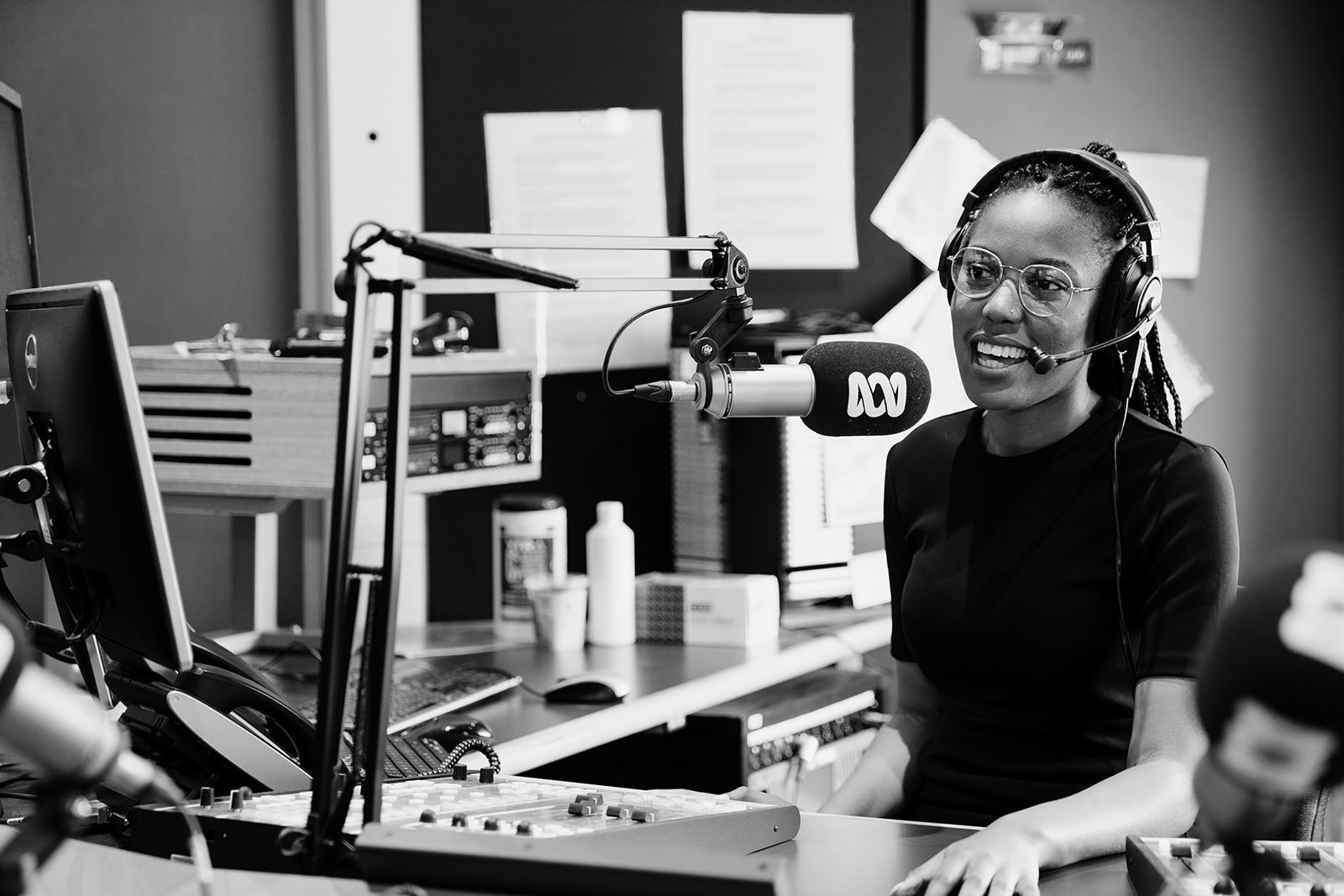 Black and white photo of a woman presenter wearing a headset talking into a microphone in in an ABC Studio