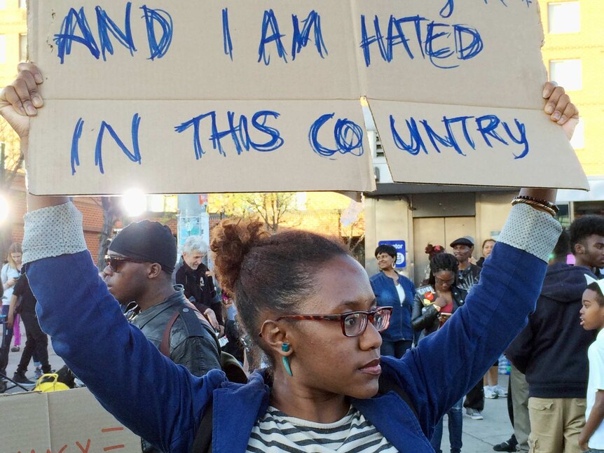 A woman holds a sign at an intersection in Baltimore