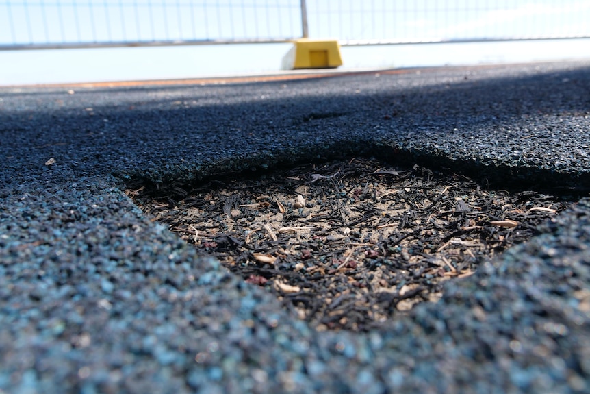 A close up photo of a soft fall playground surface crumbling into little pieces