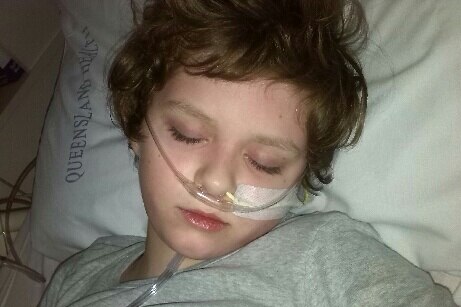 A young boy with brown hair asleep with tubes in his nose.