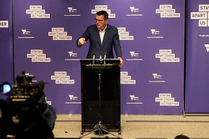 A wide shot of a Daniel Andrews press conference including the Auslan translator and TV cameras.