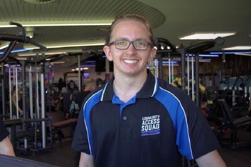 A young man wearing glasses smiles.