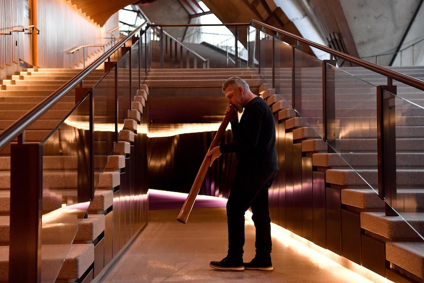 A man playing a didgeridoo inside the opera house