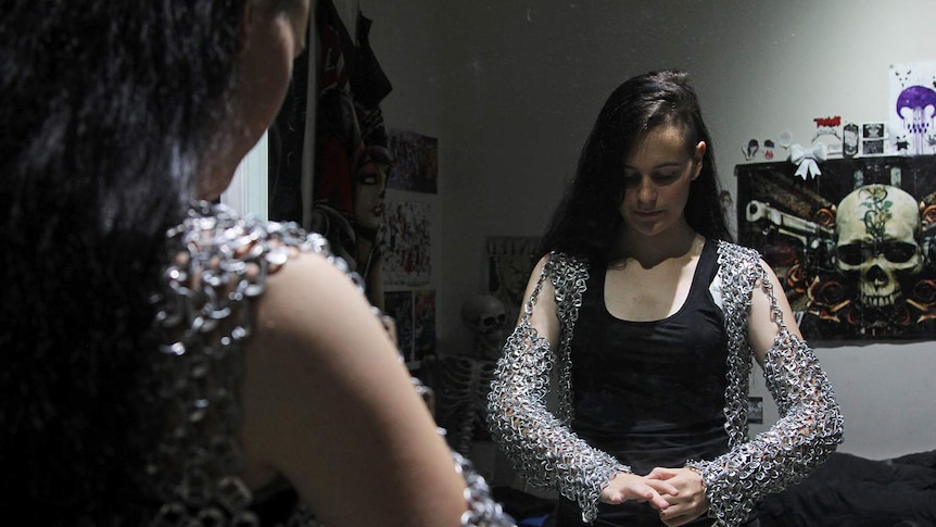 Teenager Storm Delaney stands in front of a mirror looking at the outfit she crafted.