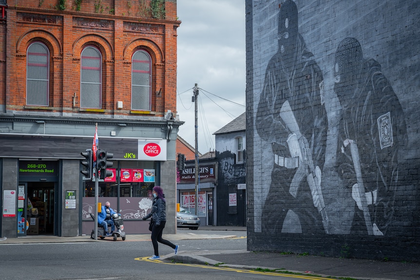 A woman walks past a mural.