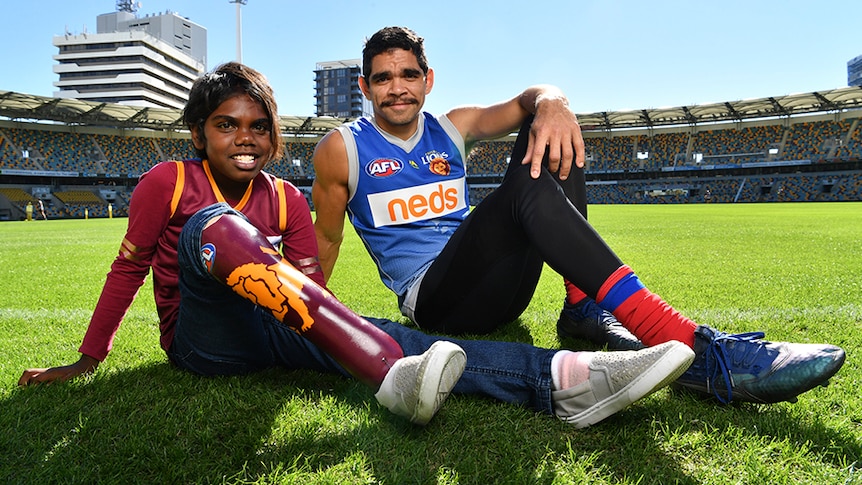Young Aboriginal girl with prosthetic leg and a man in sport uniform