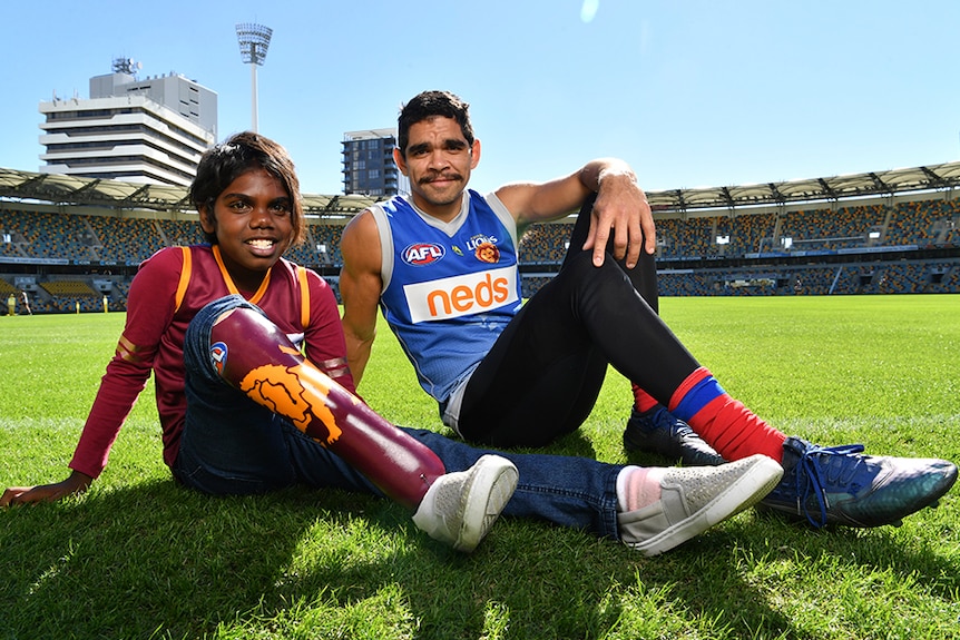 Young Aboriginal girl with prosthetic leg and a man in sport uniform