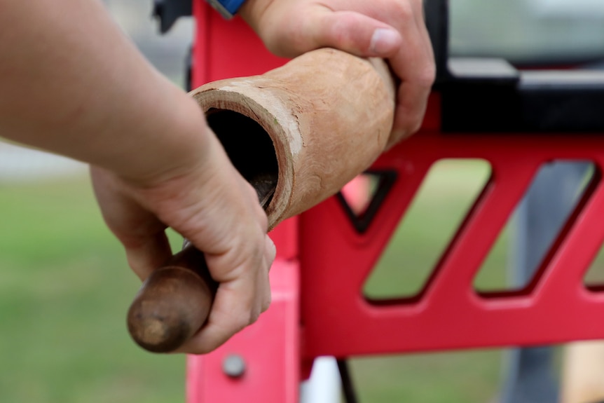 Closeup photo of a hand filing the inside of a didgeridoo.
