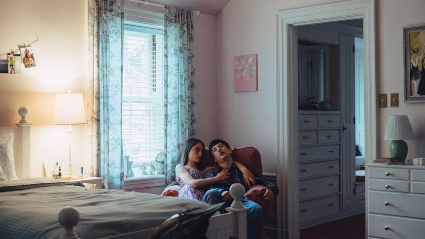 Raffey Cassidy and Barry Keoghan sitting together on a armchair in a bedroom in 2017 film The Killing of a Sacred Deer