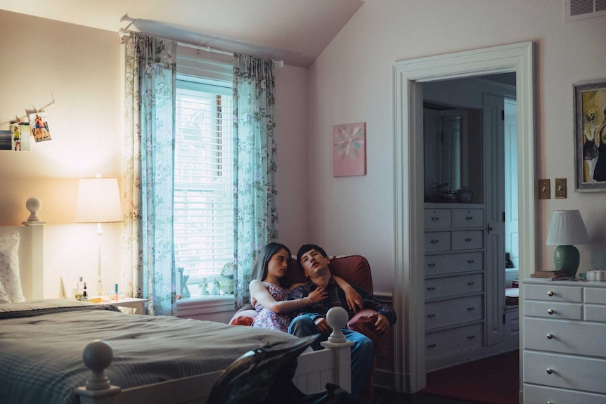 Raffey Cassidy and Barry Keoghan sitting together on a armchair in a bedroom in 2017 film The Killing of a Sacred Deer