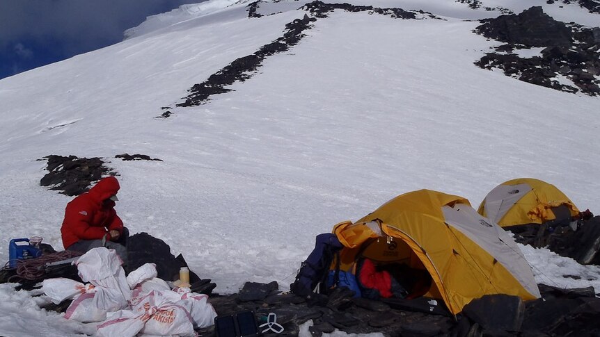 A climber stops to rest at a makeshift Noshaq camp