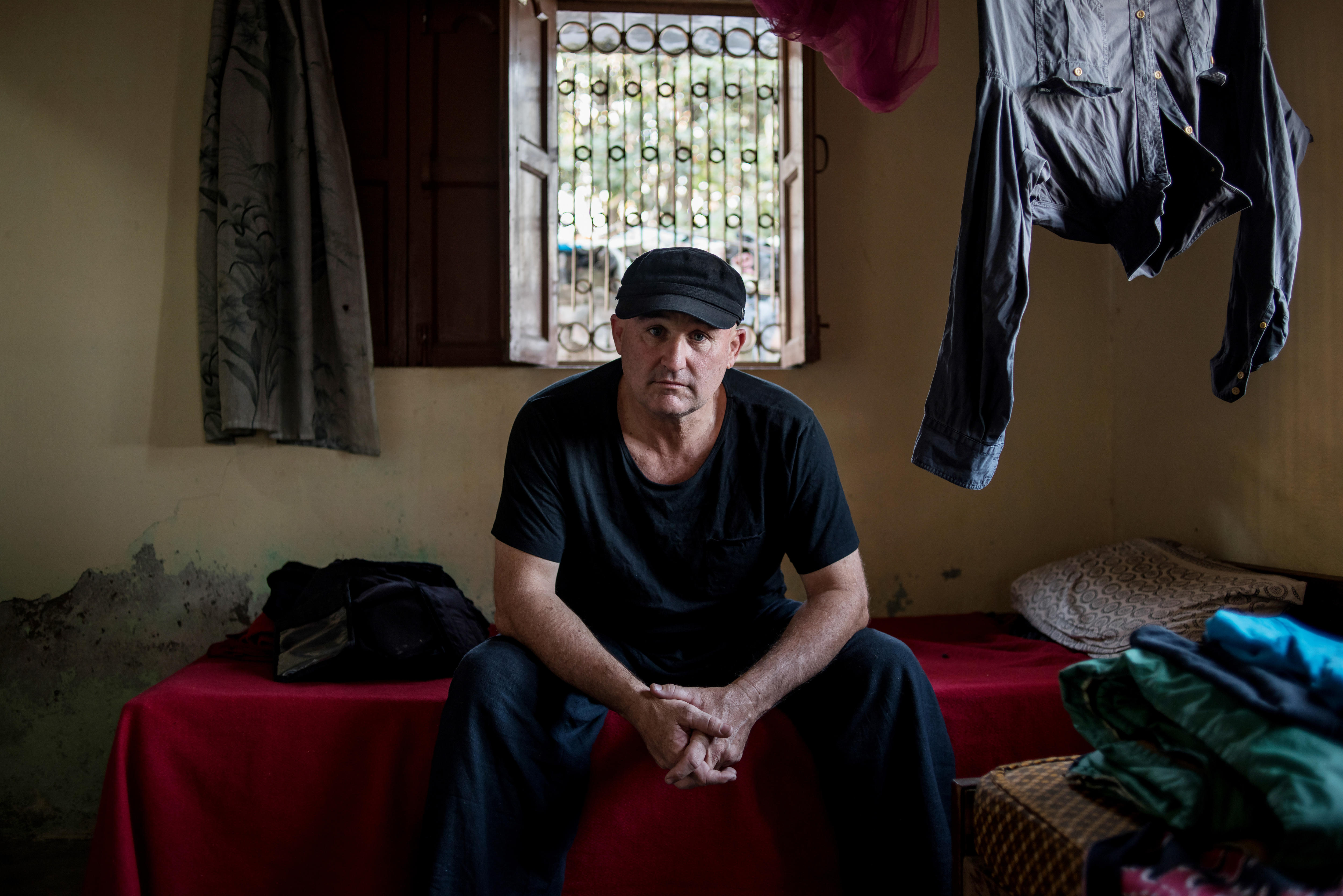 Man sitting on a bed looking at the camera.