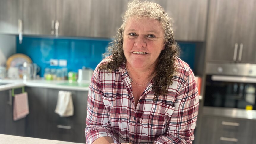 Carol Johansen in a checkered shirt, standing in her kitchen.