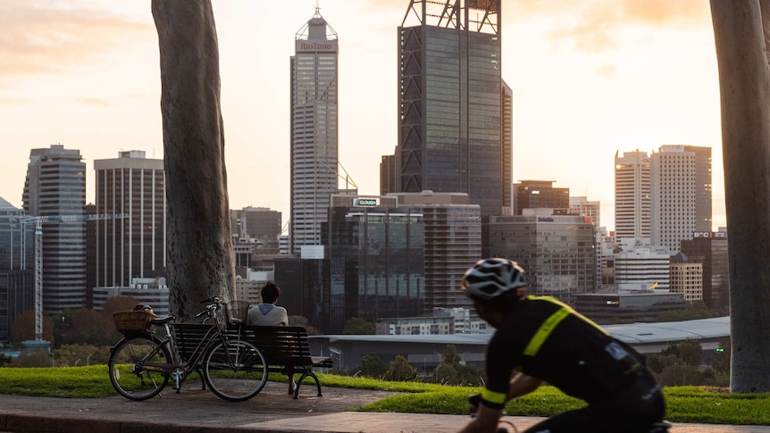 People cycle along a road overlooking a city skyline