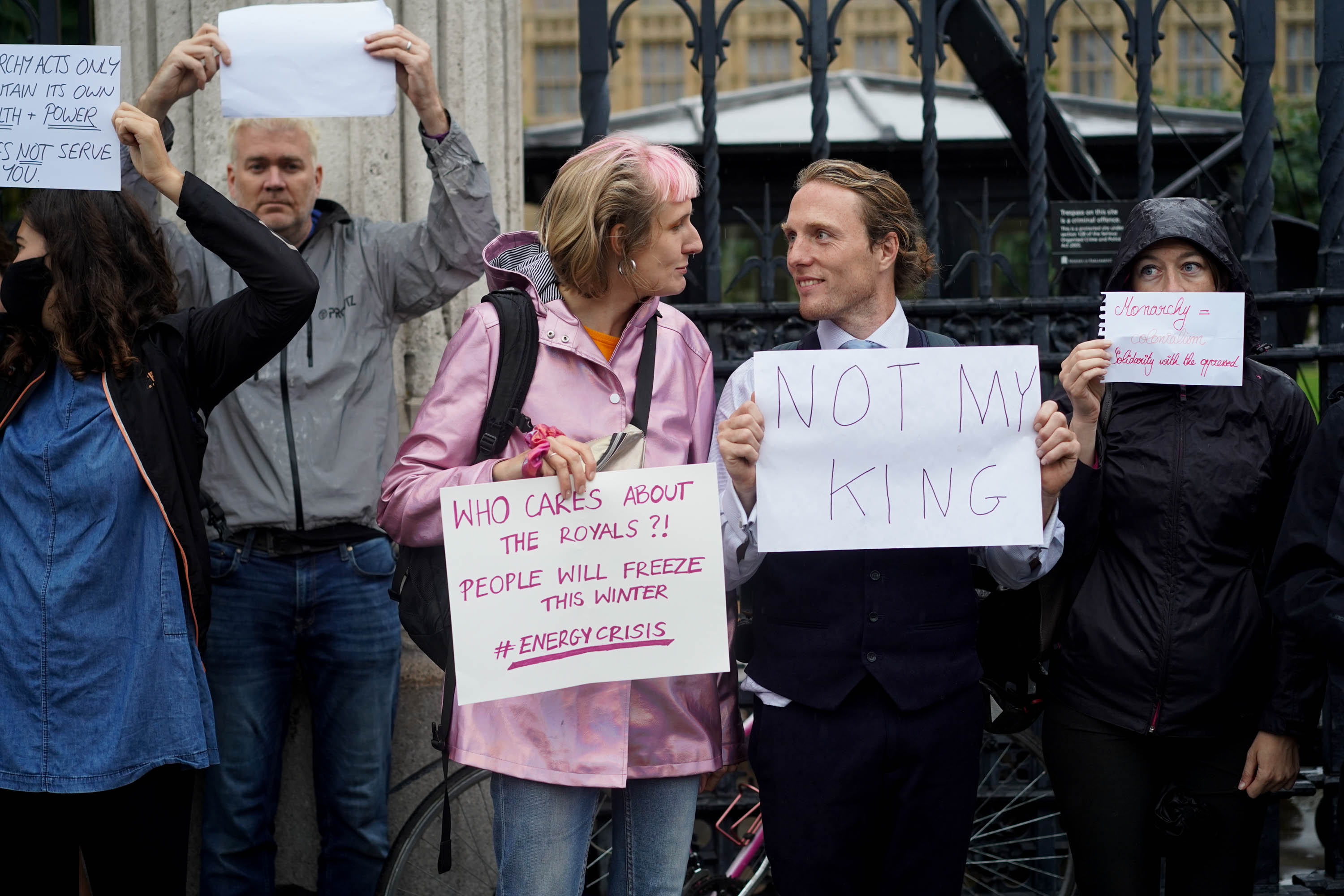 Paul stands with a 'not my king' sign and chats to another protester 