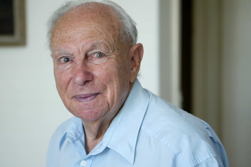 A head-and-shoulders profile shot of Dr Philip Opas at his home, wearing a light blue collared shirt.