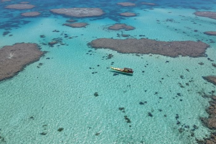An aerial shot of a fishing vessel on a sublime-looking reef.