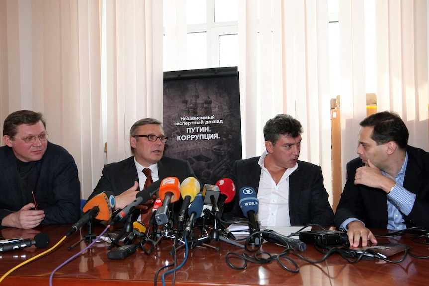 Milov, right, speaks to a colleague as part of a panel of four men holding a press conference