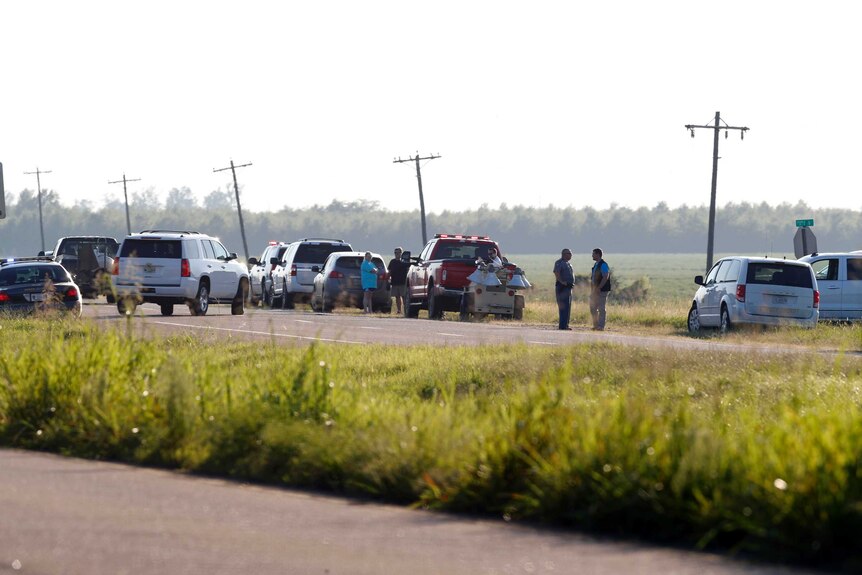A line of cars crowds the shoulder of a highway next to a Mississippi field.