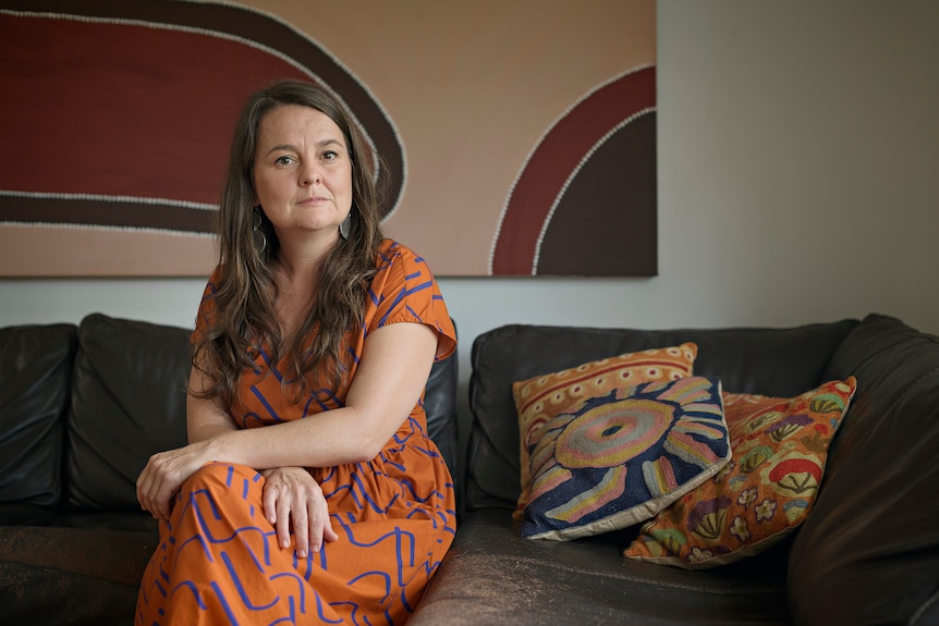 Sue Phoo sits on her couch and looks at the camera in her home 