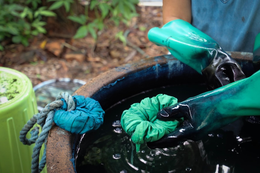 A close up of fabric being dyed with indigo in a pot.