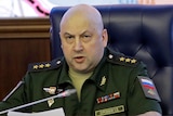 Colonel General Sergei Surovikin speaks with a map of Syria projected on the screen in the back