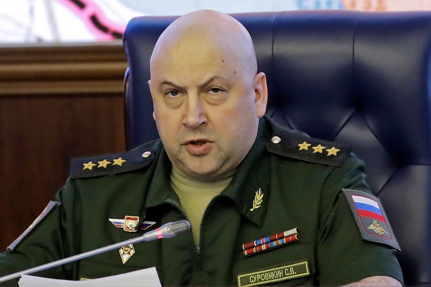 Colonel General Sergei Surovikin speaks with a map of Syria projected on the screen in the back