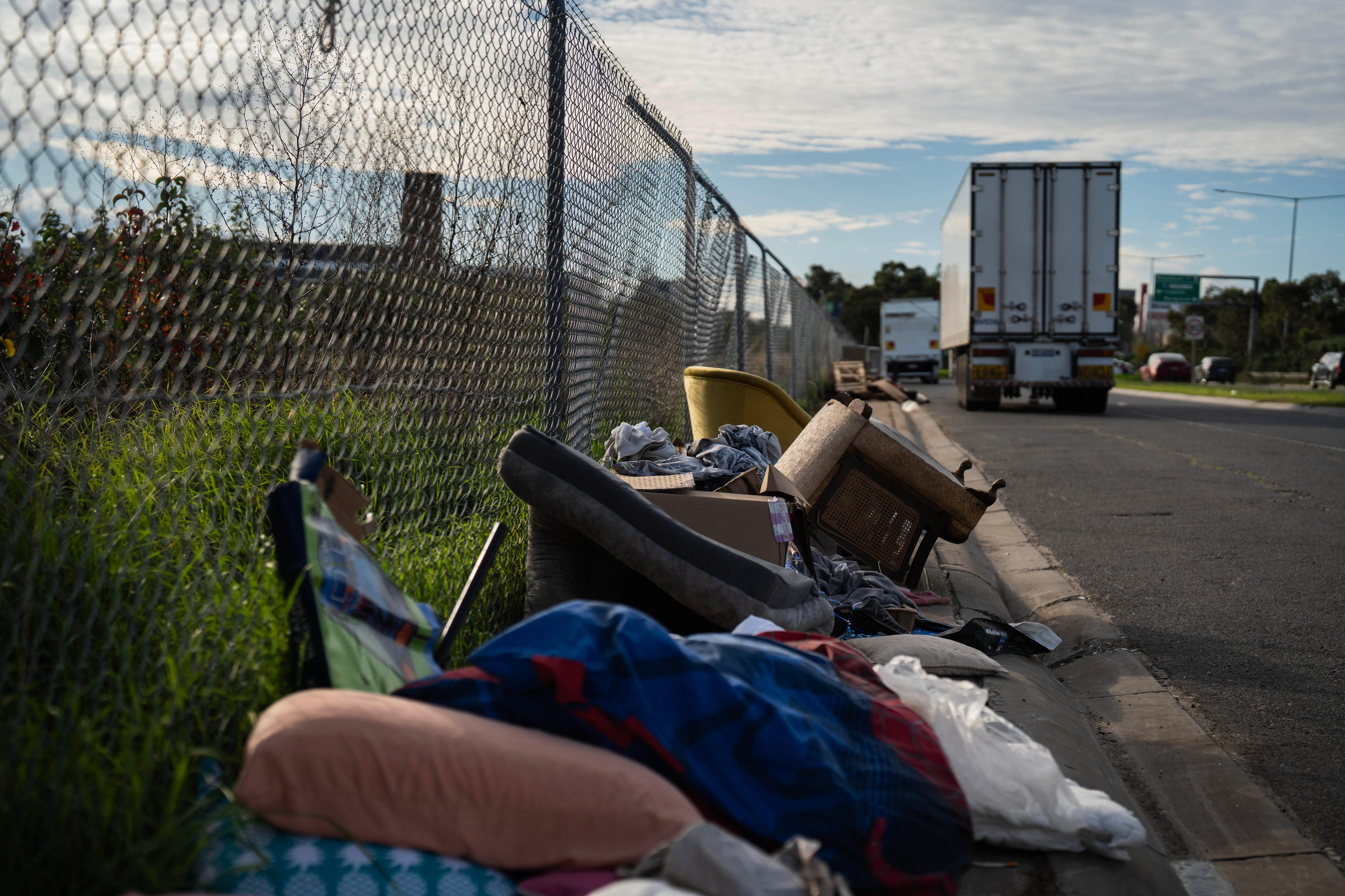 Rubbish piled up along a fence in a truck parking bay