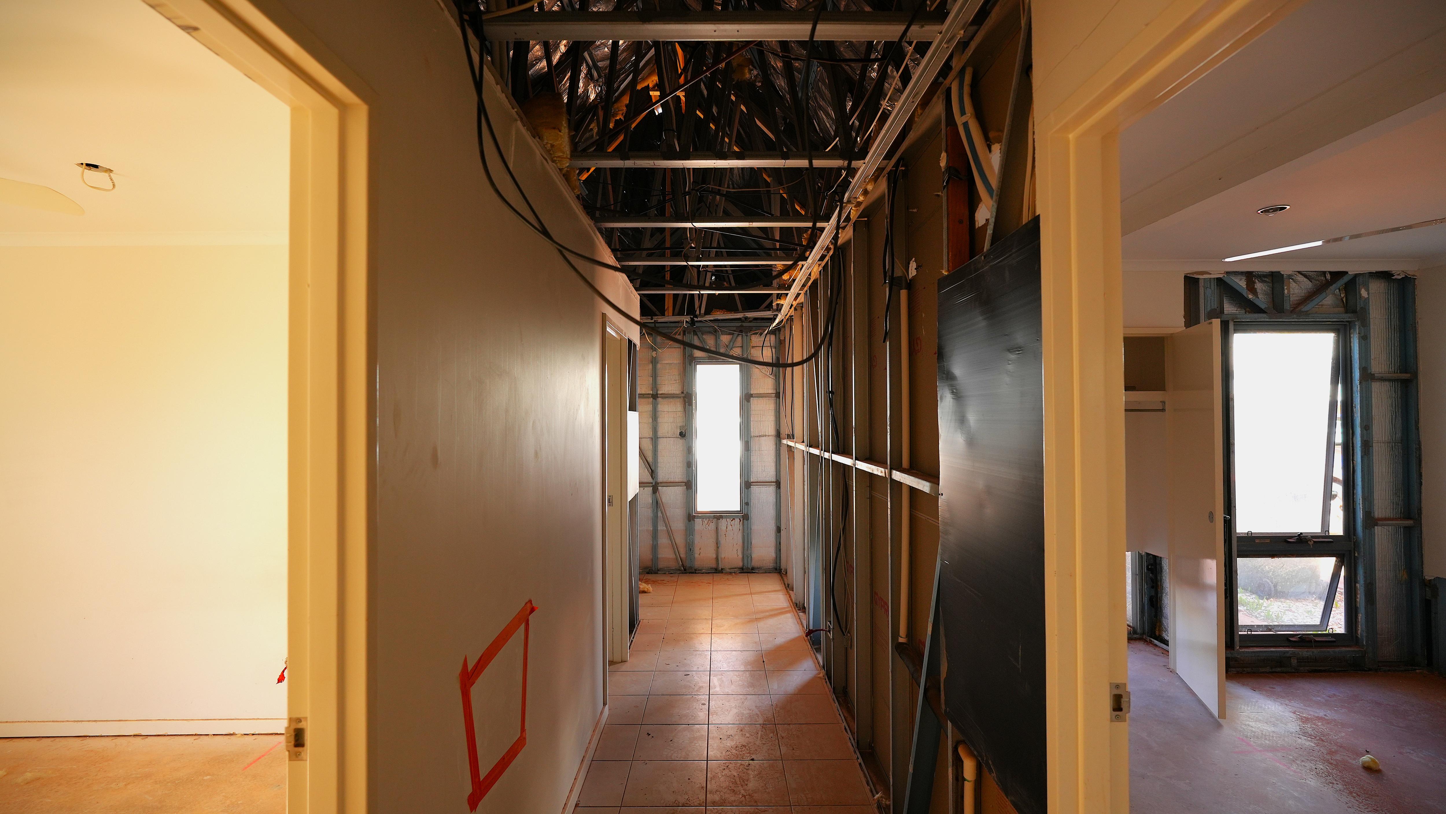 A hallway of a house with extensive wall, floor and ceiling damages.