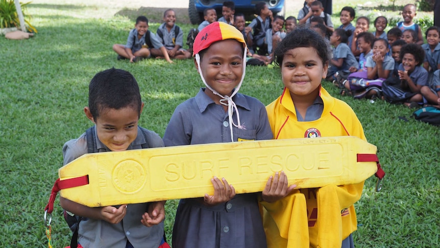 Fijian kids holding surf rescue equipment
