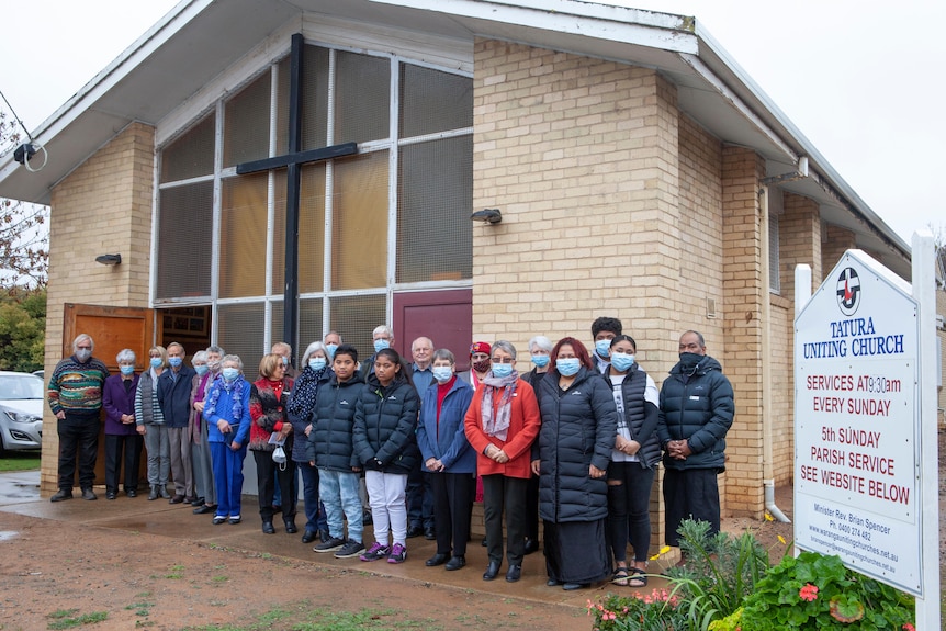 A crowd of people stand in front of a church